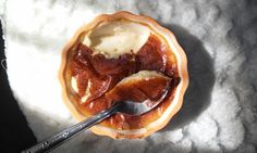 a bowl filled with pudding on top of a white table cloth next to a spoon