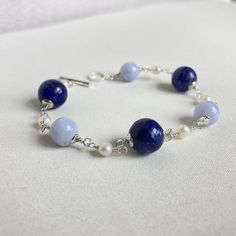 Rosary bracelet with natural Lapis Lazuli, natural blue Chalcedony and white freshwater pearls with 925 silver. The stones are of high quality in color and size. T-bar clasp and 925 silver components. Artisanal creation, entirely done by hand. For any changes contact me without hesitation. Thank you. Length: 18 cm (7.08 inches) Lapis: 9.5/10 mm. Chalcedony: 8 mm. Pearls: 4 mm. After inspection it will be packaged in a nice gift box. Model ready for delivery. Blue Pearl Bracelet With Gemstone Beads For Gift, Blue Pearl Bracelet With Gemstone Beads As A Gift, Handmade Elegant Blue Pearl Bracelet, Elegant Handmade Blue Pearl Bracelet, Elegant Handmade Lapis Lazuli Bracelets, Blue Pearl Bracelets For Jewelry Making, Blue Natural Stones Sterling Silver Bracelets, Elegant Blue Round Pearl Bracelet, Elegant Blue Pearl Bracelet