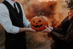 two people dressed up as witches holding a pumpkin