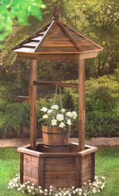 an outdoor wooden gazebo with flowers in the potted planter and on the ground