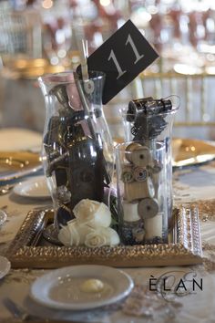 the table is set up with candles and flowers in glass vases, which have numbers on them