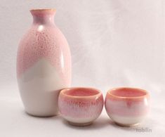 three pink and white vases sitting next to each other in front of a white background