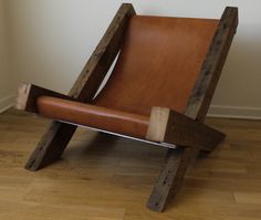 a brown leather chair sitting on top of a hard wood floor next to a white wall