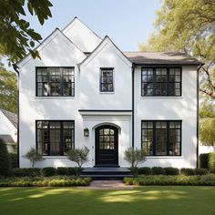 a large white house with black windows and trimmings on the front door is surrounded by greenery