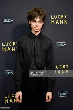 a young man in black shirt and tie standing on the red carpet at lucky hank