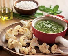 a wooden tray topped with cauliflower and green sauce