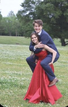 two people are posing for a photo in the grass