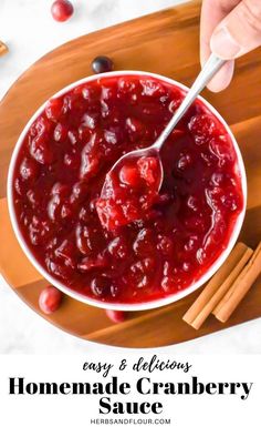 a person spooning cranberry sauce into a bowl with cinnamon sticks on the side