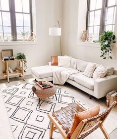 a living room filled with lots of furniture next to two large windows and a rug on the floor