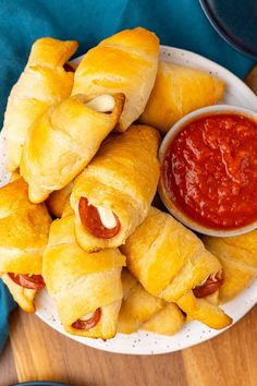 several pastries on a white plate with dipping sauce in the bowl next to them