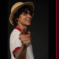 a young man wearing a straw hat and holding a toothbrush in one hand while pointing to the side