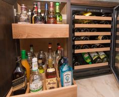 an open refrigerator filled with lots of bottles and liquor in it's drawer area