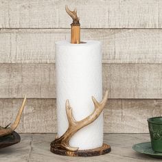 a toilet paper holder with deer antlers on it and a cup next to it