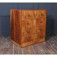 a wooden dresser sitting on top of a hard wood floor next to a blue wall