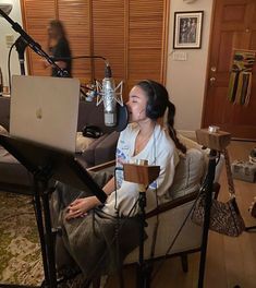 a woman sitting in a chair with a laptop on her lap, and a microphone behind her