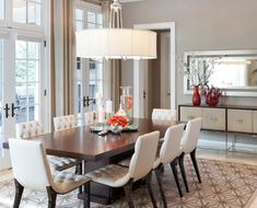 a dining room table with white chairs and a chandelier