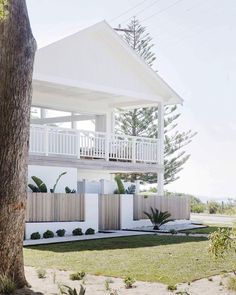 a large white house sitting on top of a lush green field next to a tree