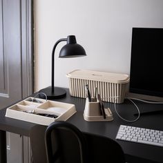 a desk with a computer monitor, keyboard and mouse on it next to a lamp