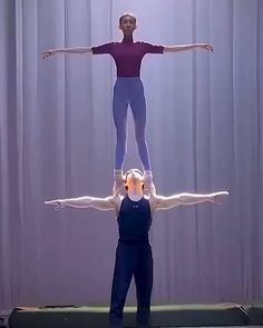 two people doing acrobatic tricks in front of a curtain