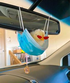 a duck wearing a face mask hanging from a car mirror