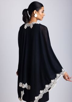 This elegant black knitted cape, crafted from a very soft 100% merino wool, combines warmth and refined designing. The delicate scalloped beige-colored filigree lace border creates a striking contrast against the black wool, adding a touch of sophistication and unique charm. Its soft, free-flowing silhouette makes it a versatile accessory. Whether for daytime outings or evening events, this timeless cape is designed to keep you stylishly cozy while making a bold statement. A must-have piece for Elegant Crochet Lace Cardigan, Elegant Black Poncho Cape, Elegant Black Cape Poncho, Knitted Cape, Wool Cape, Free Flowing, Lace Border, Unique Charms, Black Knit