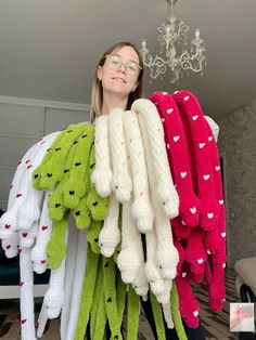 a woman standing next to a bunch of stuffed animals on top of each other in front of a chandelier