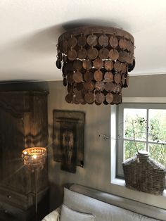 a living room with a couch and a lamp hanging from the ceiling next to a window