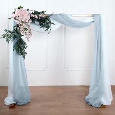 an arch decorated with flowers and greenery for a wedding ceremony or special occasion in front of a white wall