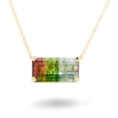 Description: This solitaire drop pendant necklace captures a striking and unique gem: a natural tri-color tourmaline. The tourmaline is an emerald cut set sideways in a sturdy, secure 4-prong basket setting connected directly to the necklace. The gem weighs approximately 3.15 carats and fades in color from a vibrant pink to a soothing green to a cool light blue. The necklace measures 18 3/8 inches long and uses a lobster clasp to secure it. The tourmaline is October's birthstone. This pendant necklace is brand new. Specs: Material info: Solid 14Kt (585) Yellow GoldTotal Gram Weight: 3.2 GramsClasp: Lobster Gemstone Information: 1 Emerald Cut 4-Prong Set Natural Tri-Color TourmalineColor: Pink, Green, Light BlueCut: Cut Cornered Rectangular Step CutTransparency: TransparentCarat Weight: App Basket Setting, Drop Pendant Necklace, Basket Sets, Green Light, Drop Pendant, October Birth Stone, Glass Pendant, Tri Color, Emerald Cut