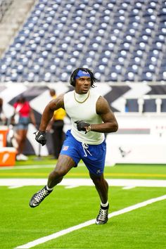 a man running across a field in blue shorts