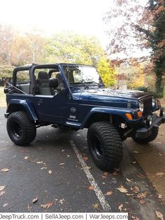 a blue jeep is parked in a parking lot with trees and leaves on the ground