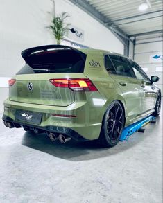 the rear end of a green car in a garage