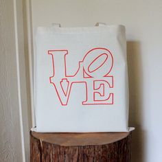 a tote bag with the word love on it sitting on top of a tree stump