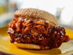 a close up of a sandwich on a plate with sesame seed crust and bbq sauce