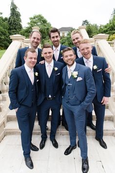 a group of men standing next to each other wearing suits and bow ties in front of a stone staircase