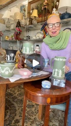 an older woman sitting at a table with two coffee mugs on top of it