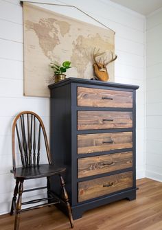 a wooden dresser sitting on top of a hard wood floor next to a black chair