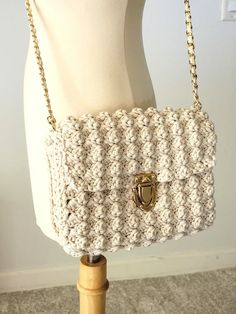 a white crocheted purse sitting on top of a mannequin