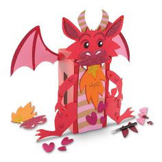 a red dragon sitting inside of a pink gift box next to cut out paper hearts