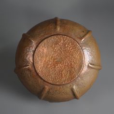 an old wooden bowl sitting on top of a gray surface with holes in the middle