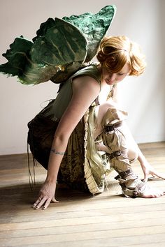 a woman sitting on the floor next to a large leafy plant in her hands