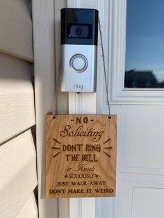 a wooden sign hanging from the side of a door with a camera attached to it