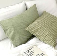 a bed with two pillows and a book on top of it next to the pillow