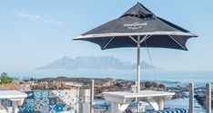 an umbrella and two chairs on a deck overlooking the ocean