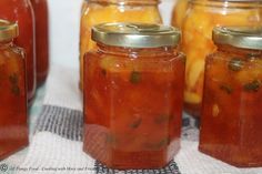 several jars filled with pickles sitting on top of a cloth covered table next to each other