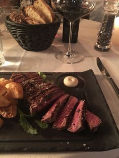 a steak dinner is served on a black plate