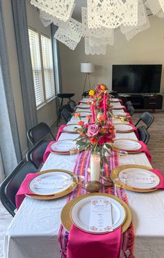 a long table set with place settings and flowers