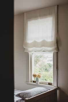 a vase with flowers sitting on top of a window sill next to a bed