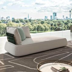 a modern daybed in front of a large window overlooking a cityscape with skyscrapers