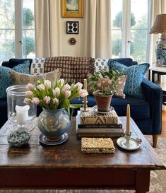 a living room filled with blue couches and flowers on top of a coffee table